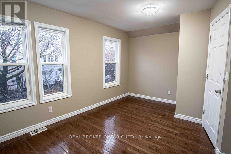 A room with wood flooring and two windows.
