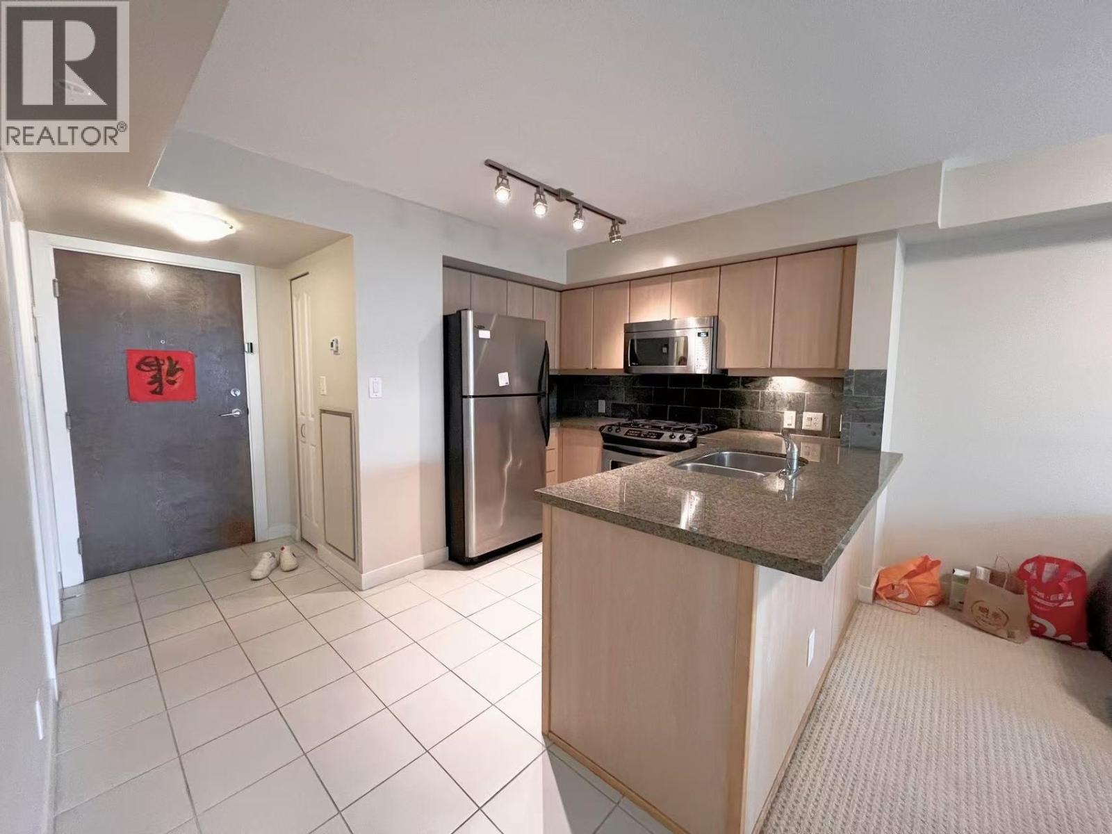A kitchen with a refrigerator, microwave, and oven.