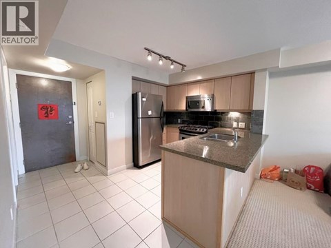 A kitchen with a refrigerator, microwave, and oven.