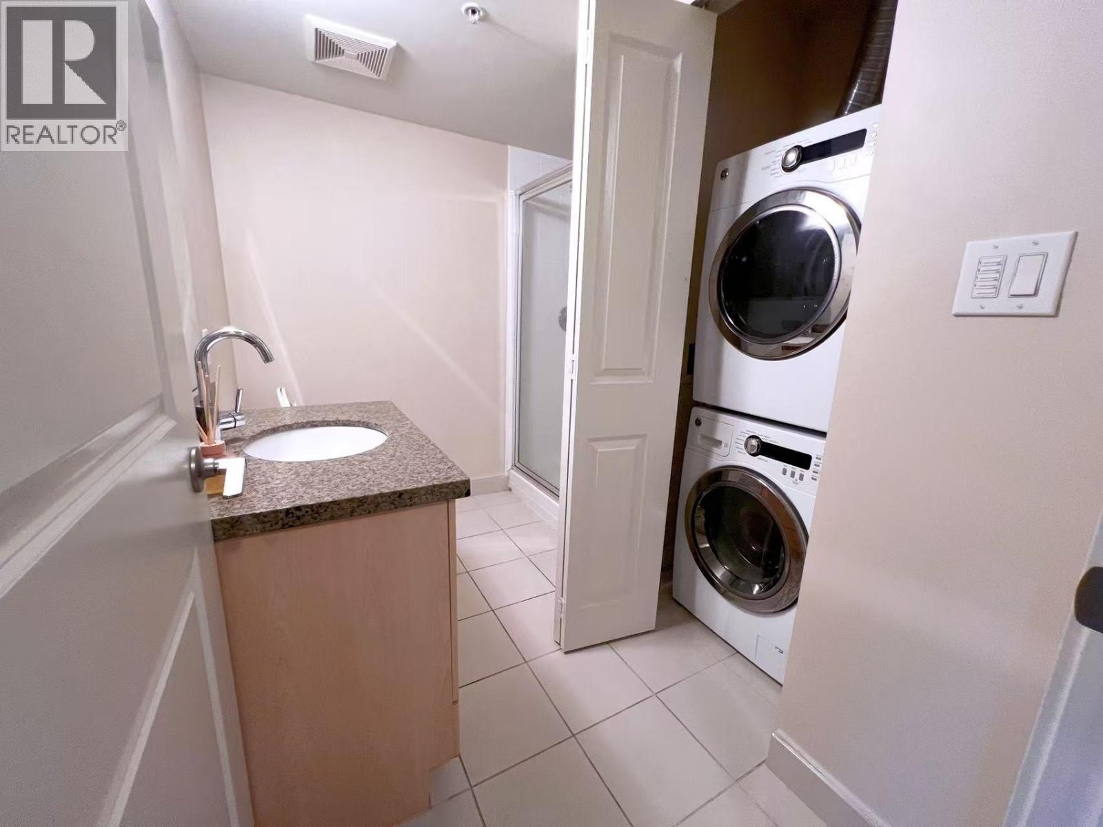 A small bathroom with a washer and dryer in the doorway.