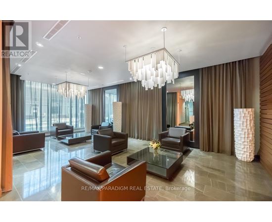 A modern living room with a glass table and brown leather couches.
