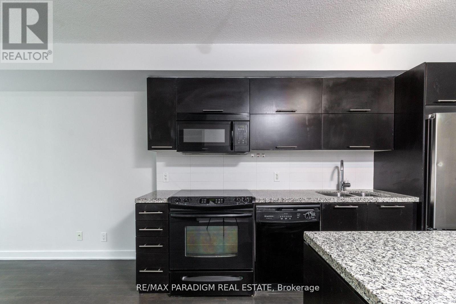 A kitchen with black cabinets and a white countertop.