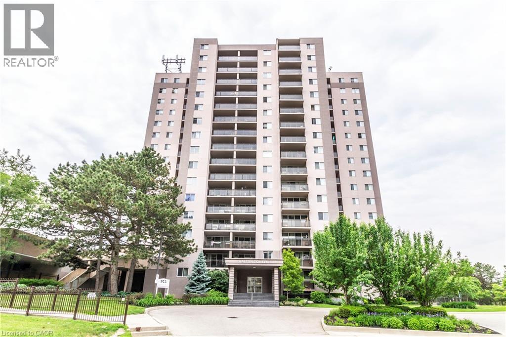 A tall residential building with a green lawn in front.