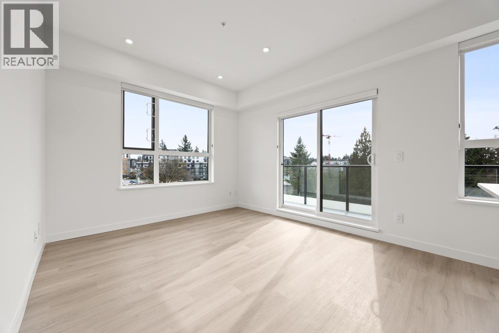 A spacious room with wooden flooring and large windows.