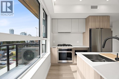 A modern kitchen with a stainless steel refrigerator and a view of the city.