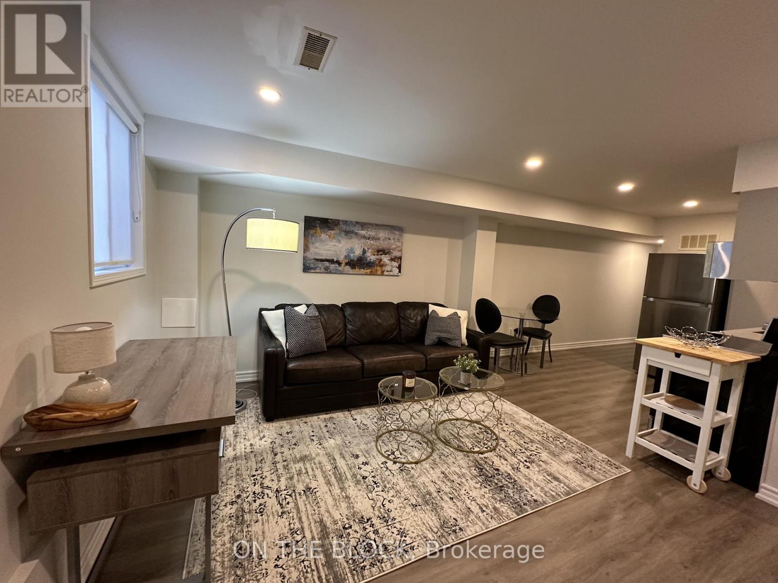 A living room with a black couch and a rug on the floor.