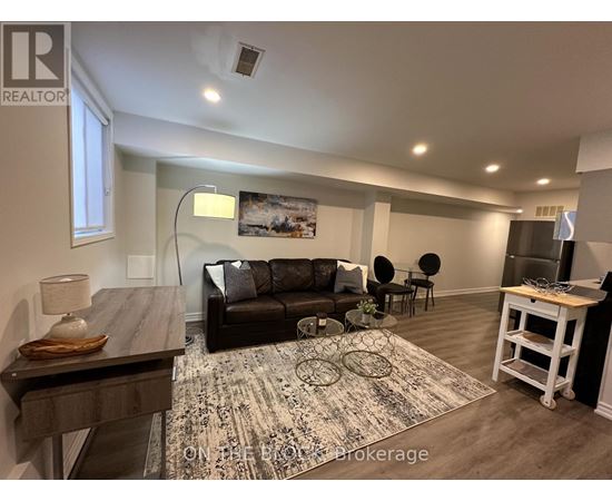 A living room with a black couch and a rug on the floor.