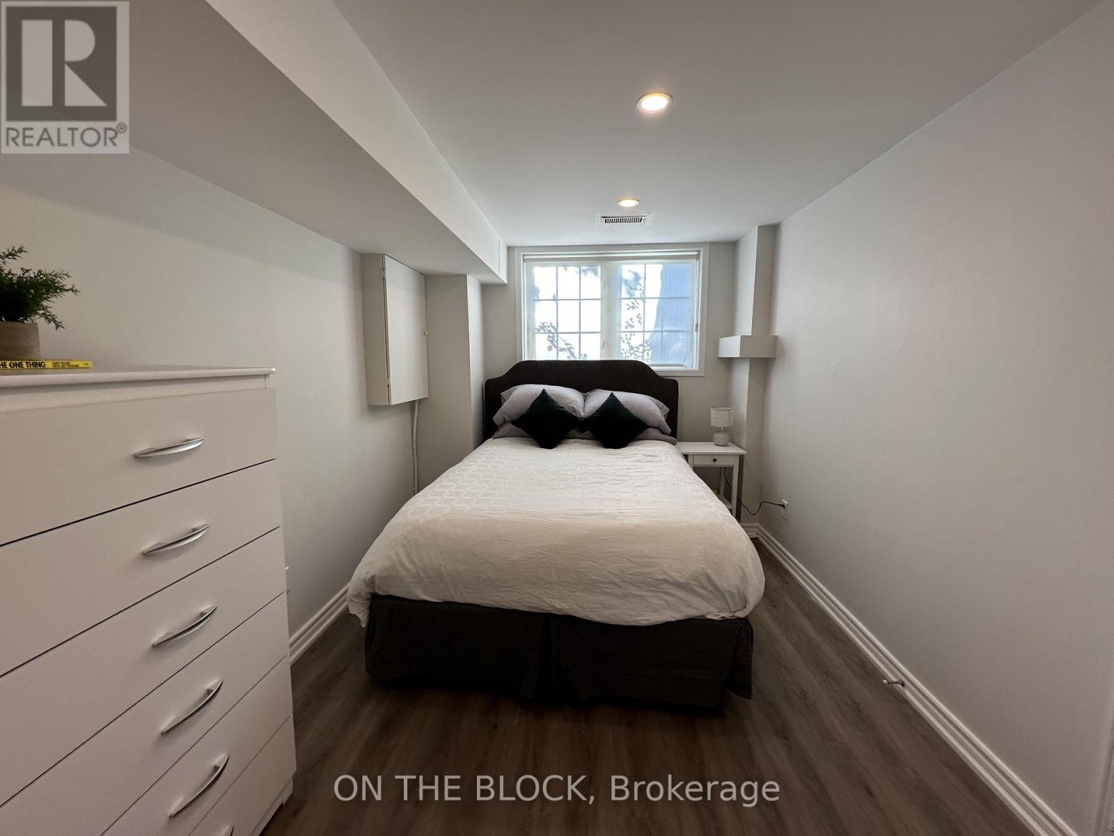 A bedroom with a bed, dresser, and window.