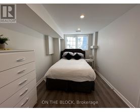 A bedroom with a bed, dresser, and window.