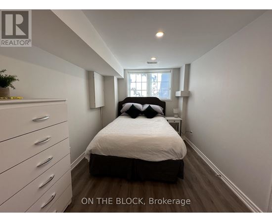 A bedroom with a bed, dresser, and window.