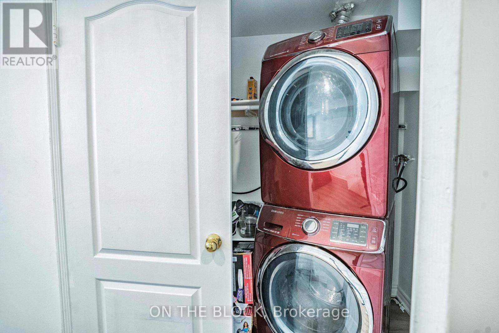 A red washing machine is stacked on top of another red washing machine in a small space.
