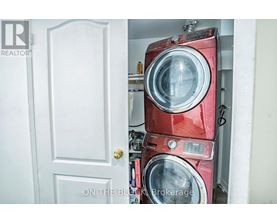 A red washing machine is stacked on top of another red washing machine in a small space.