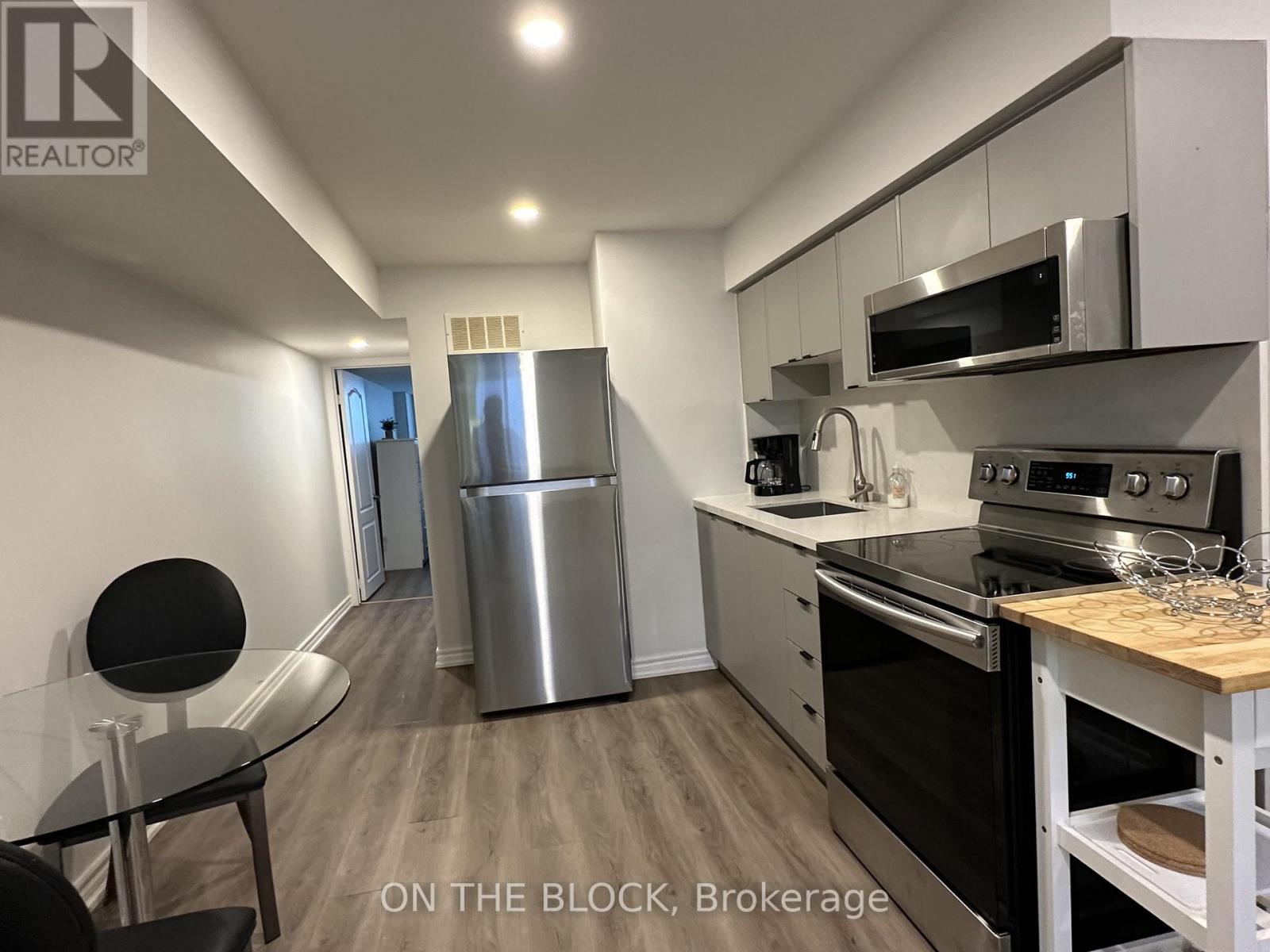 A modern kitchen with stainless steel appliances and a dining table.