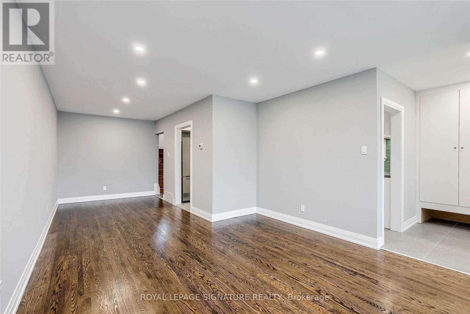 A spacious room with wooden flooring and white walls.