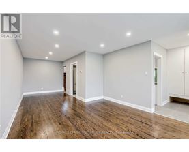 A spacious room with wooden flooring and white walls.