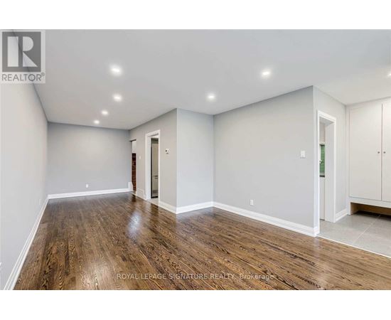 A spacious room with wooden flooring and white walls.