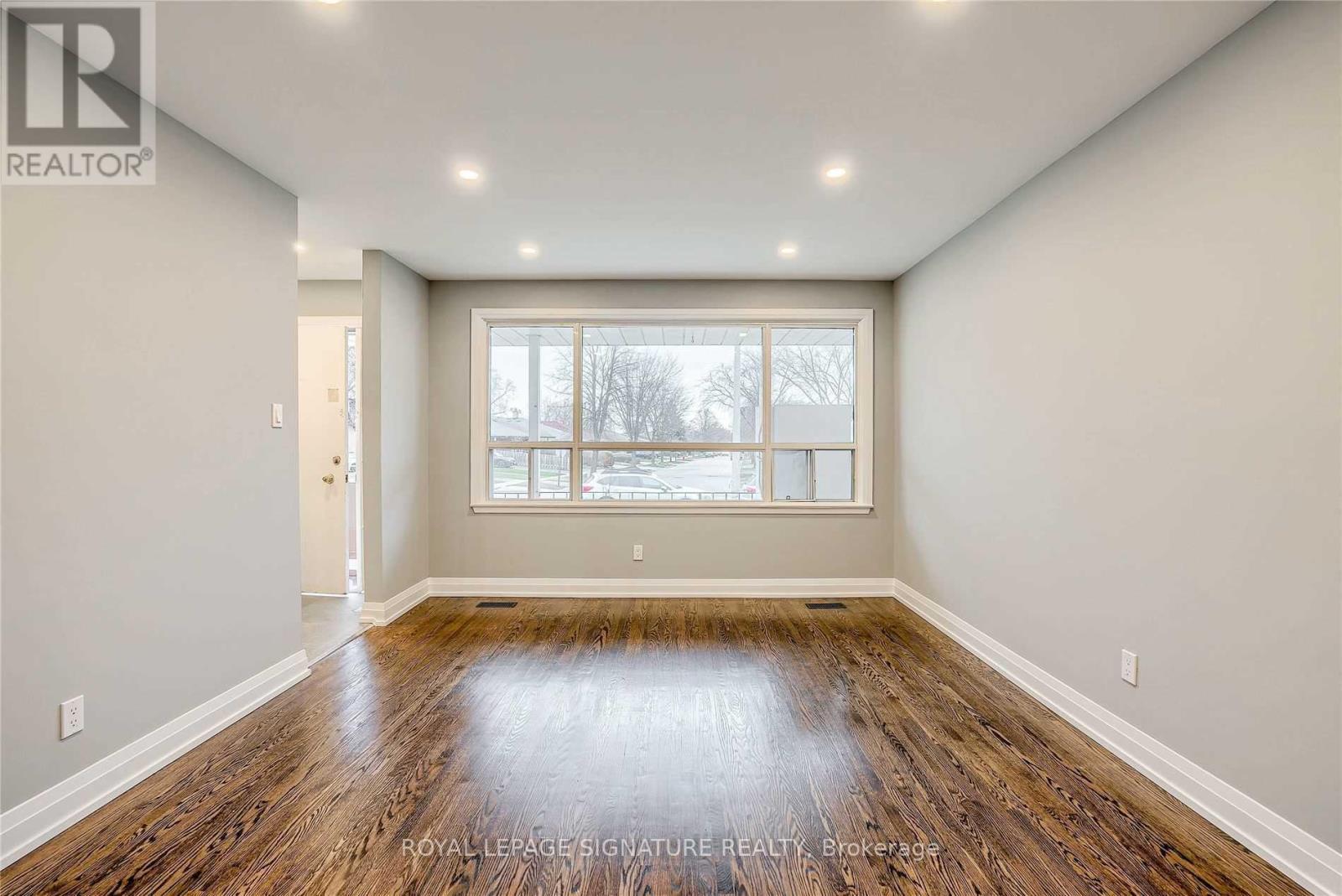 A spacious room with wooden floors and a large window.