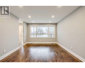 A spacious room with wooden floors and a large window.