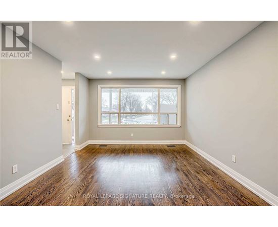 A spacious room with wooden floors and a large window.