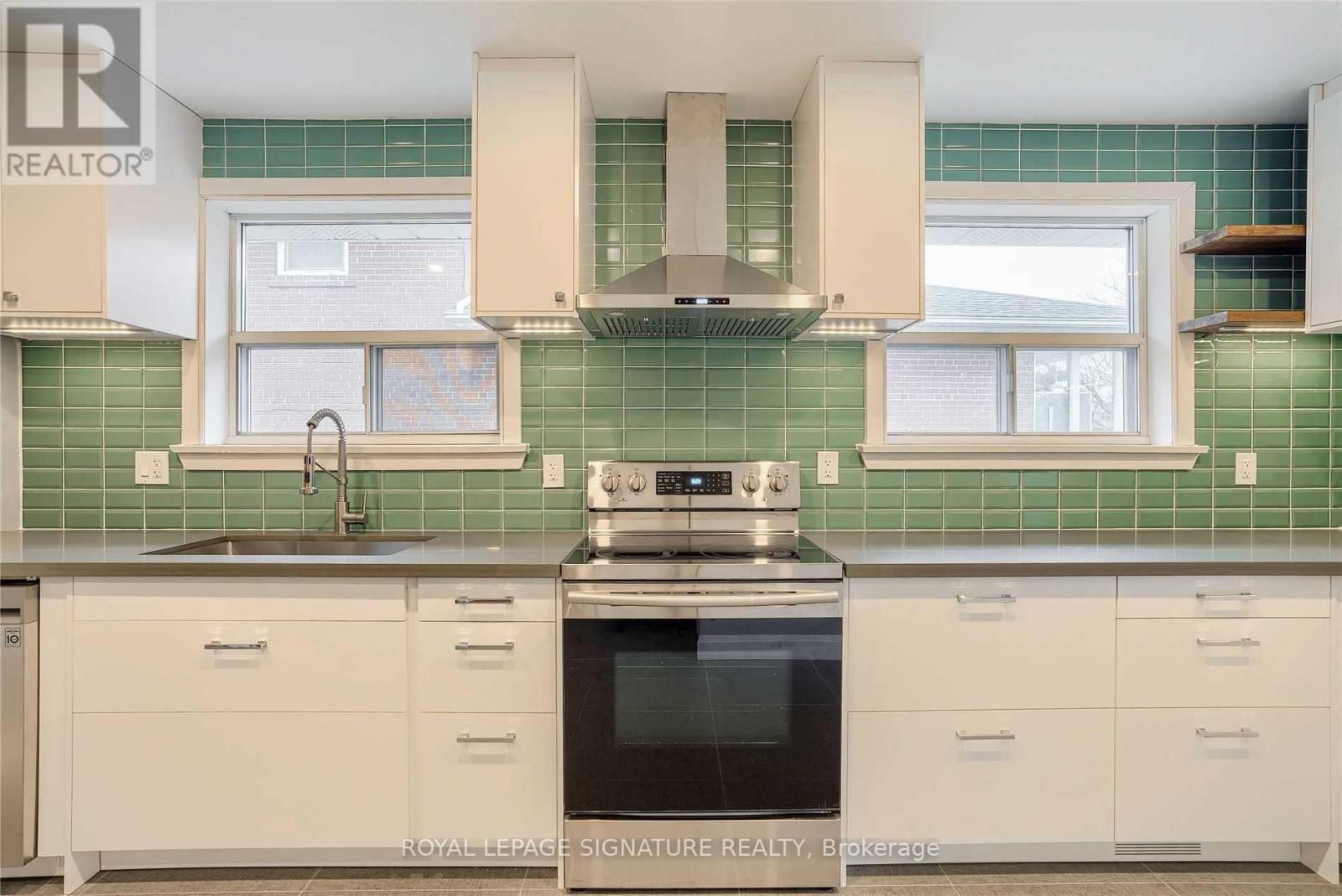 A kitchen with white cabinets and a green tile backsplash.