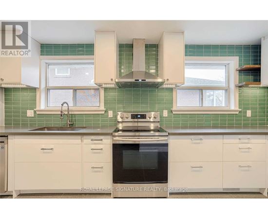 A kitchen with white cabinets and a green tile backsplash.