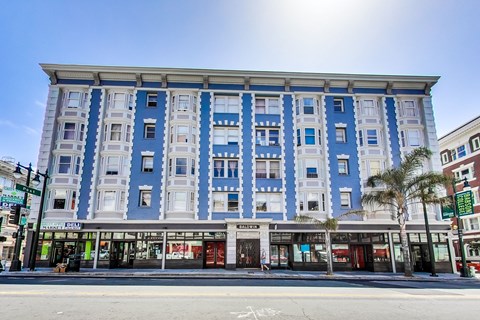 A blue and white building with shops on the ground floor.
