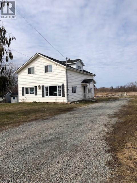 A white house with a gravel driveway in front.