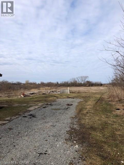 A gravel path leads through a grassy field with a fence in the distance.