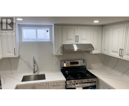 A kitchen with white cabinets and a stainless steel stove top.