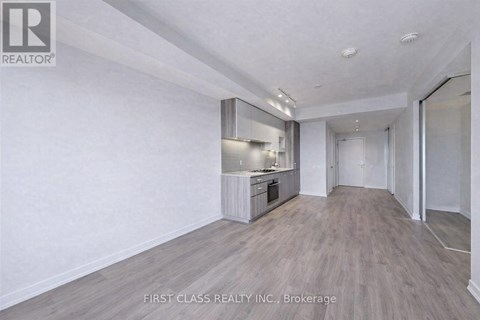 A spacious room with a kitchenette and wooden flooring.