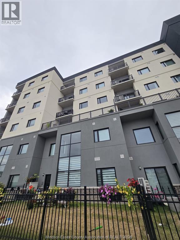 A large apartment building with a black fence in front.