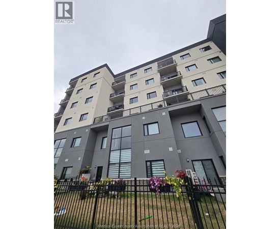 A large apartment building with a black fence in front.