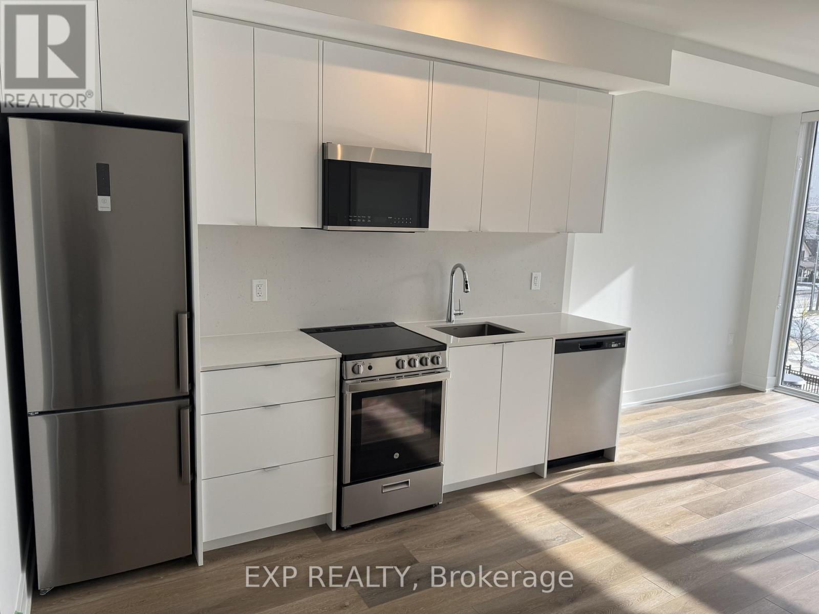 A kitchen with white cabinets and a stainless steel refrigerator.