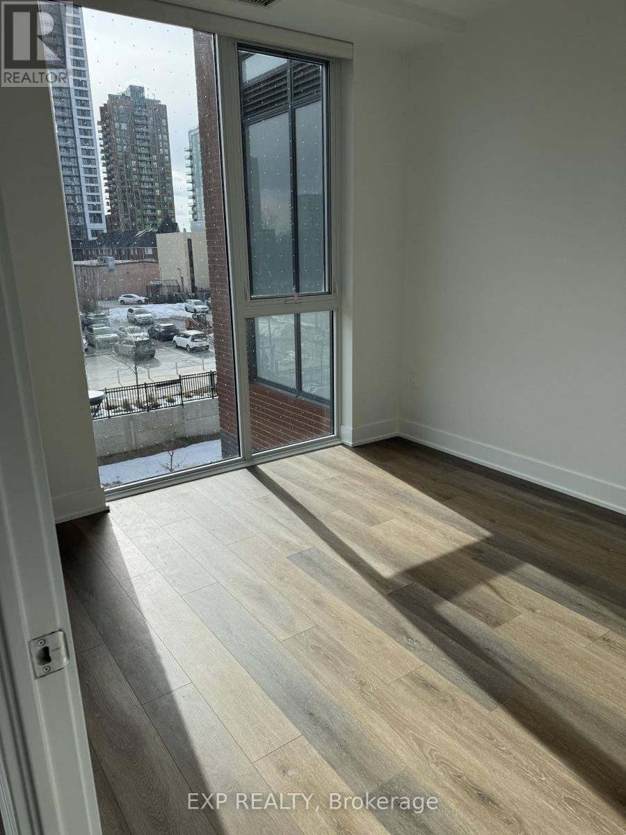 A room with a view of a parking lot and buildings outside.
