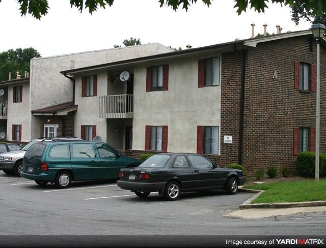 two cars parked in a parking lot in front of a building
