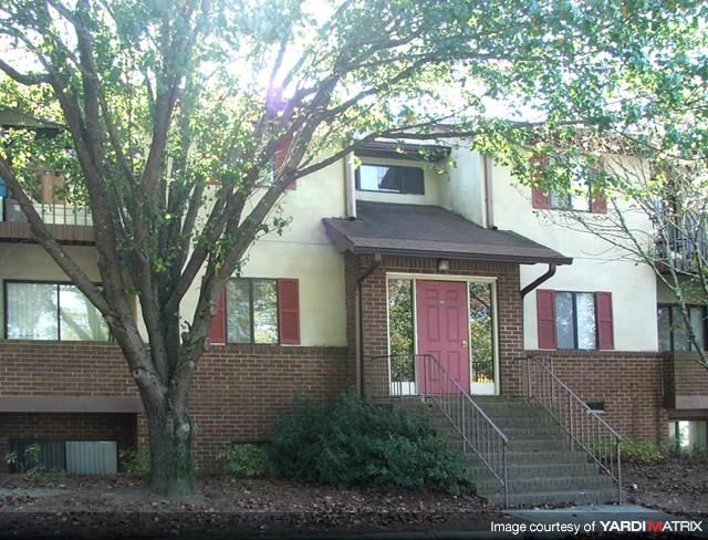 a brick house with a pink door and a tree