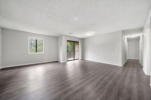an empty living room with wood floors and a door to a balcony