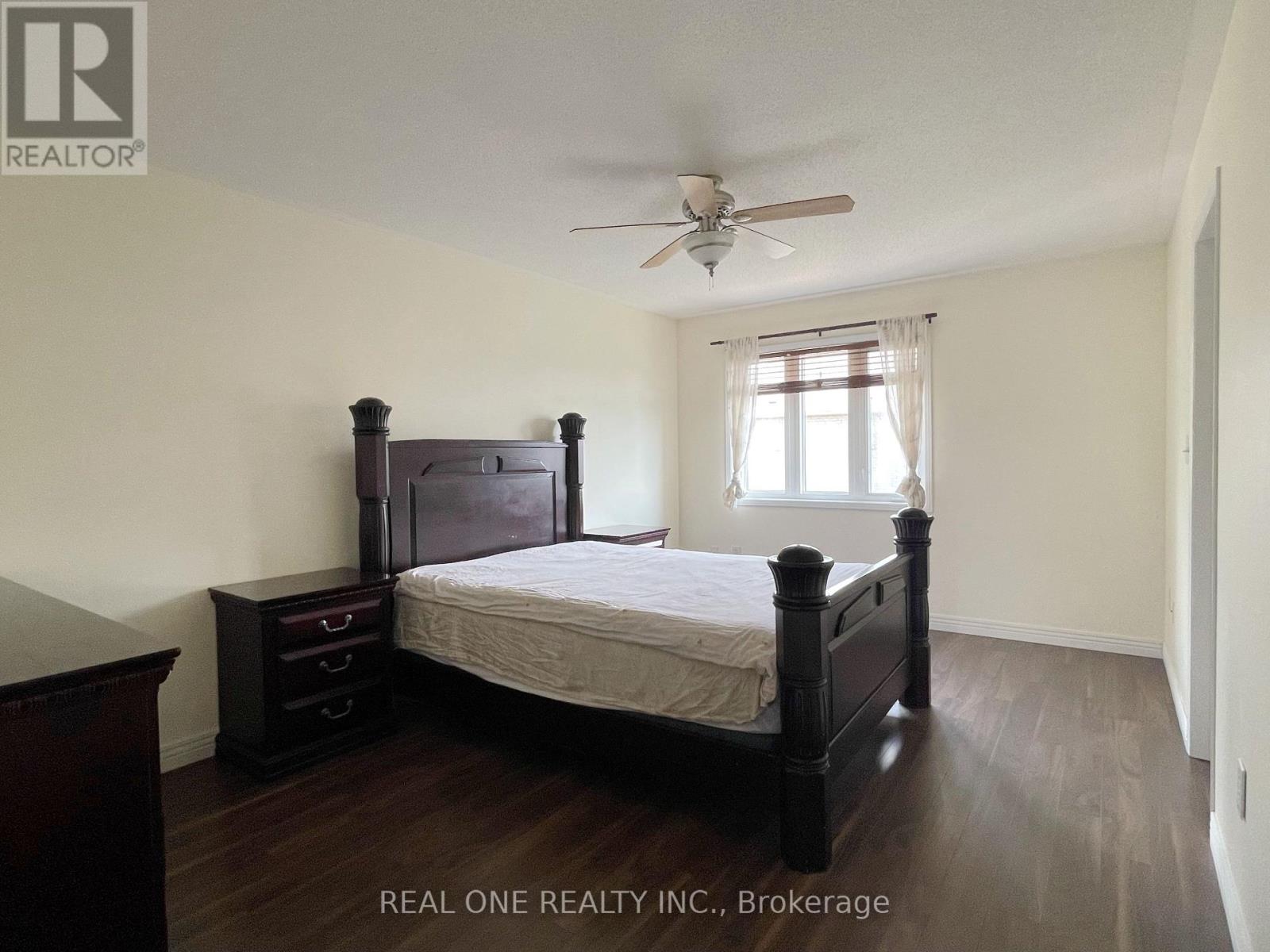 A bedroom with a bed, dresser, and window.
