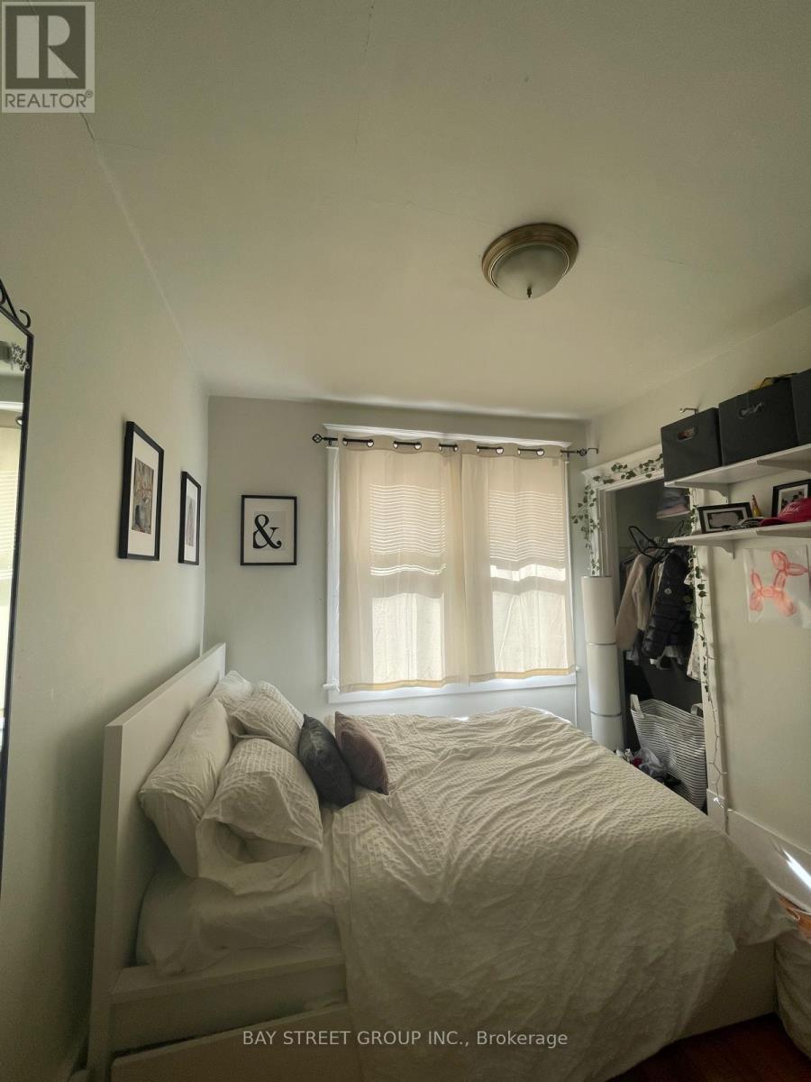 A bedroom with a bed, a window with curtains, and a shelf with various items.