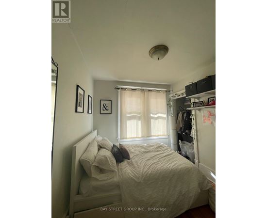 A bedroom with a bed, a window with curtains, and a shelf with various items.