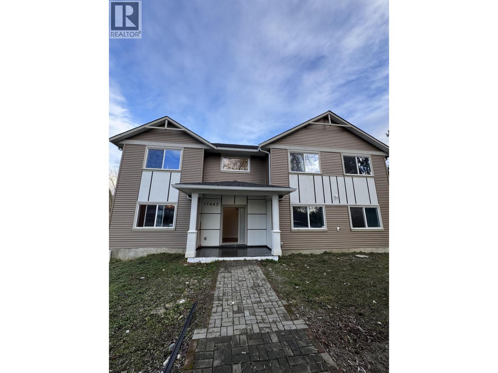 A house with a grey facade and a white door is for sale.