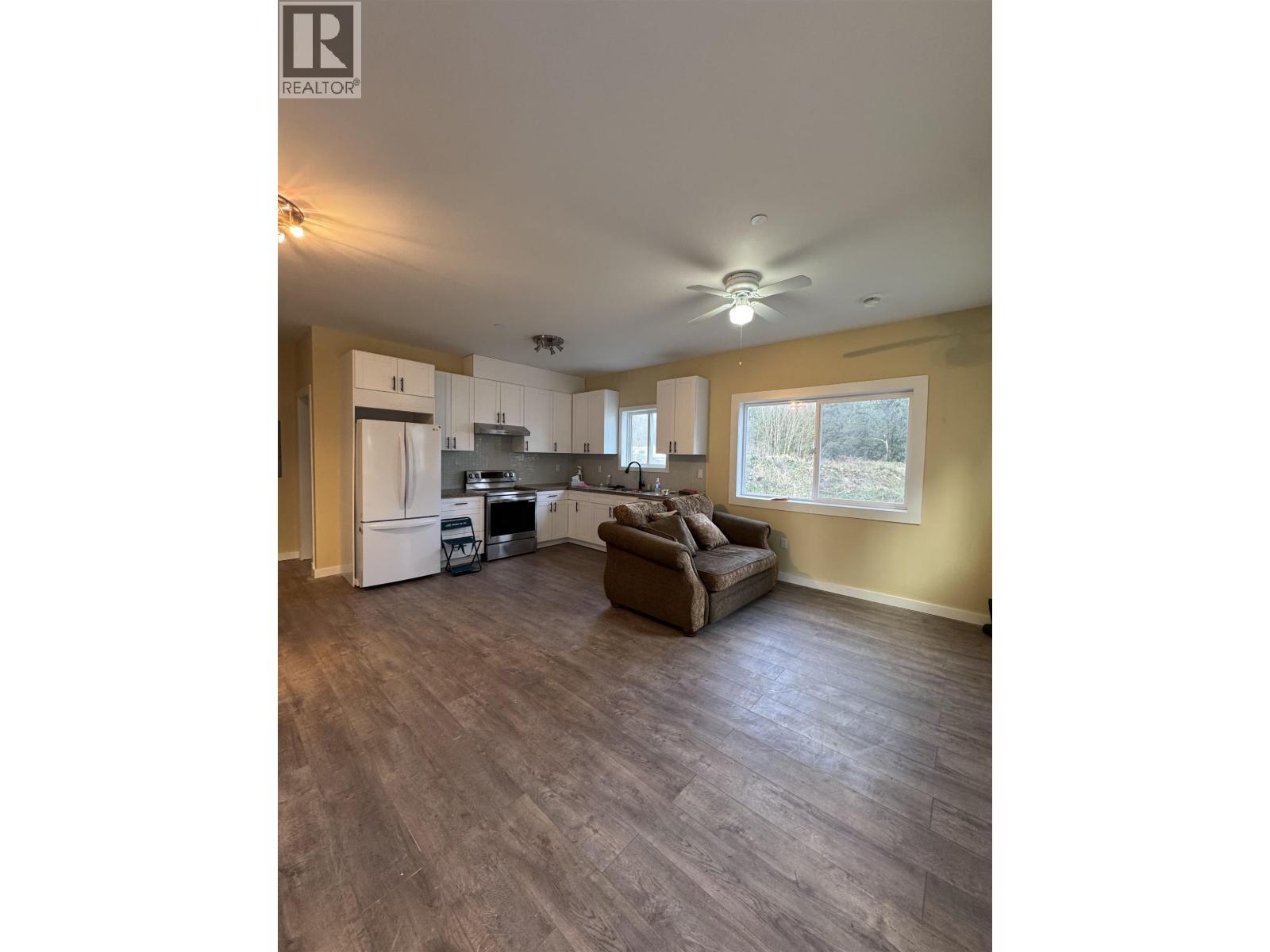 A spacious living room with a kitchen in the background.