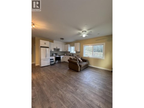 A spacious living room with a kitchen in the background.