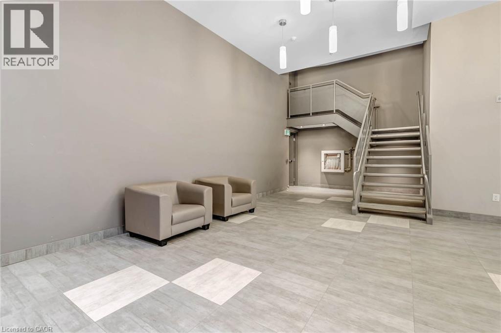 A spacious room with a staircase, two chairs, and a table.