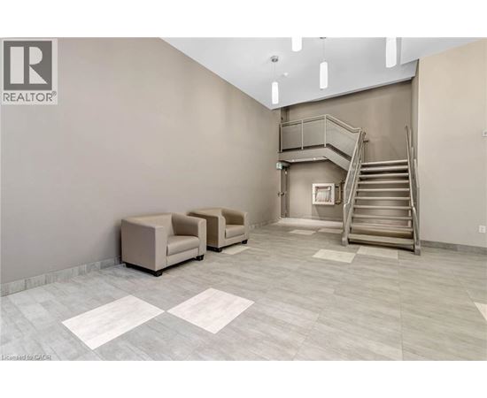 A spacious room with a staircase, two chairs, and a table.