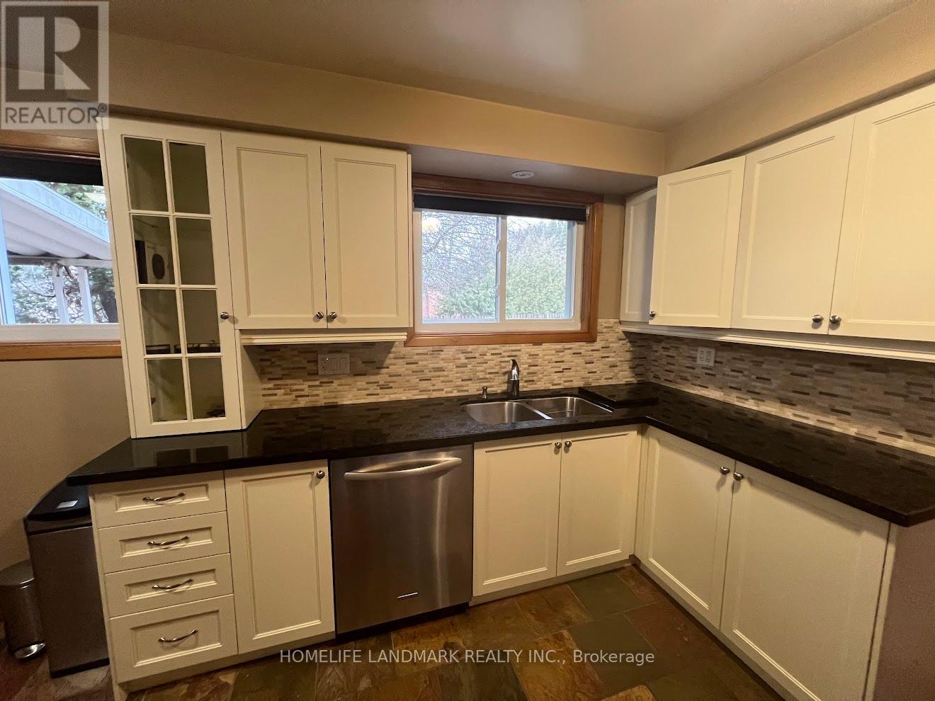 A kitchen with white cabinets and a black countertop.