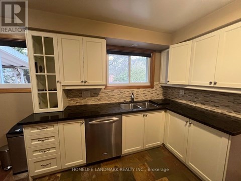 A kitchen with white cabinets and a black countertop.