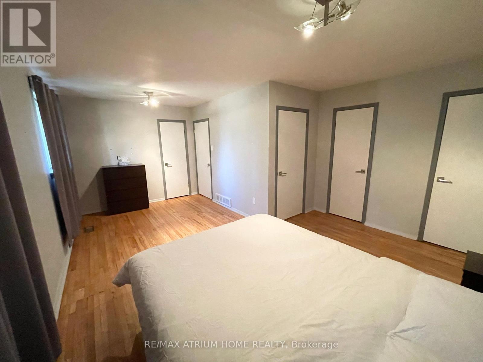 A bedroom with a large bed and a wooden floor.