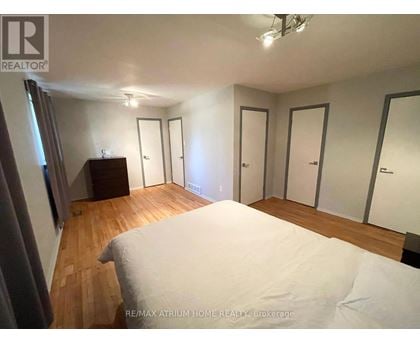 A bedroom with a large bed and a wooden floor.