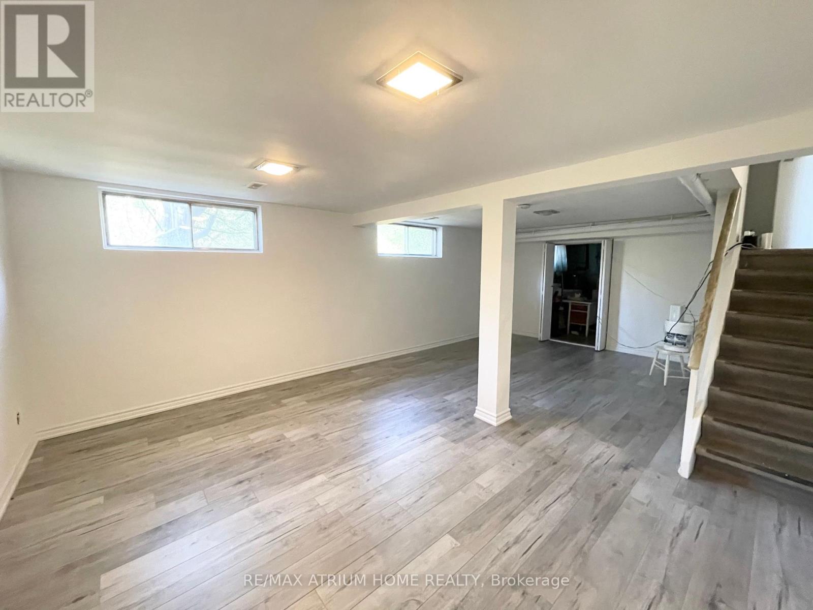 A spacious room with wooden flooring and a staircase leading to another room.